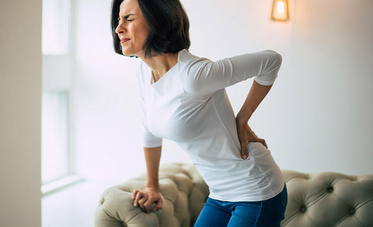 Femme souffrant d'une douleur persistante au dos.